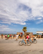 people riding a bike next to the beach